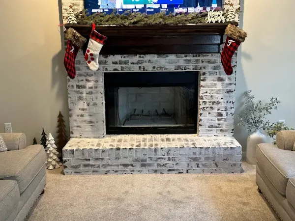 A fireplace insert in a whitewashed brick surround with stockings hung from the mantel