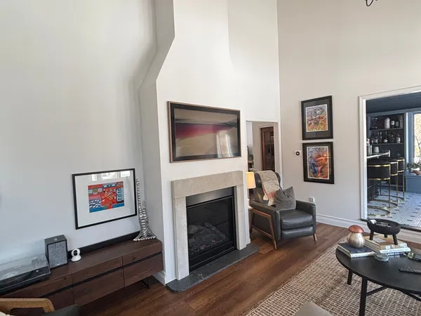 A direct-vent gas fireplace in a tall white plaster surround in a living room with hardwood floors
