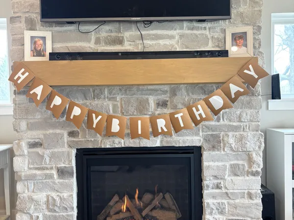 A direct-vent gas fireplace in a stone surround with a wood mantel and a TV above