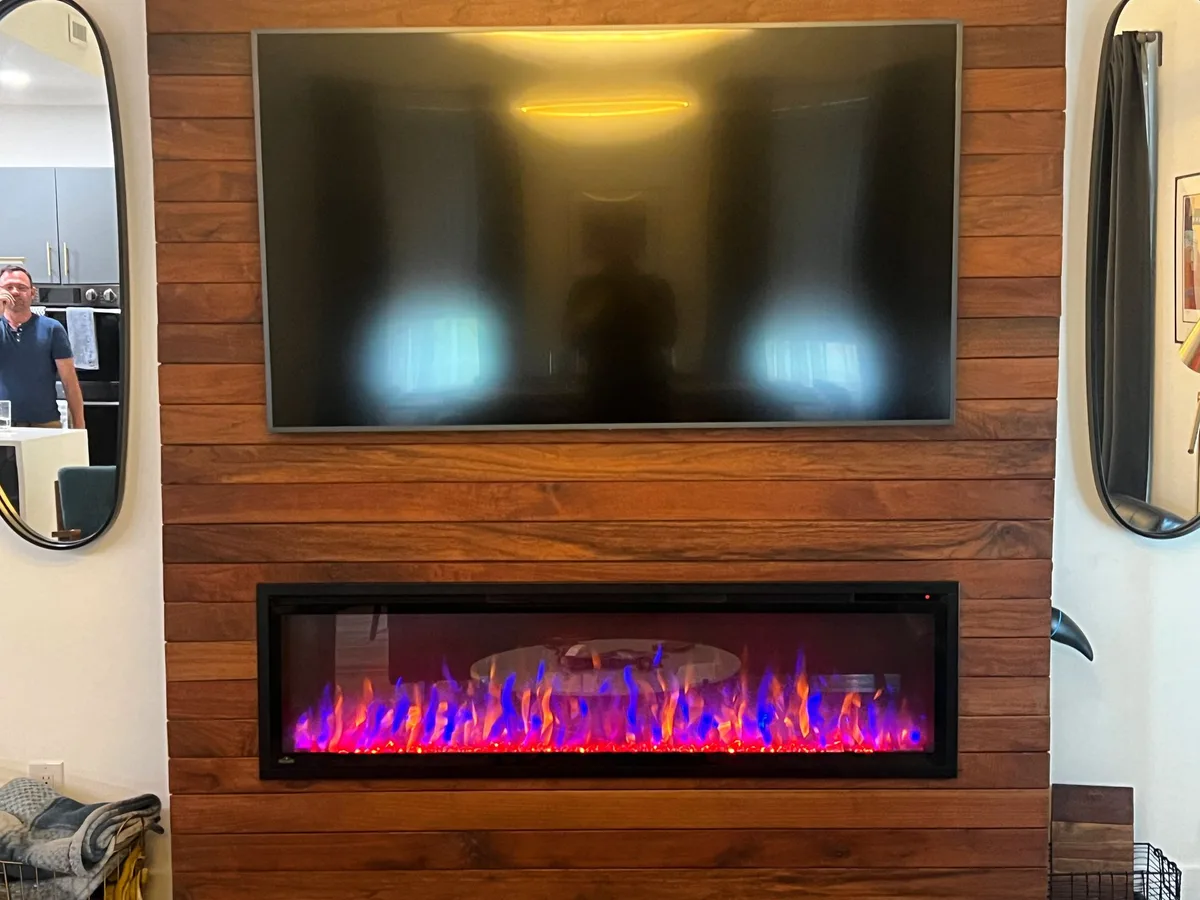 A linear electric fireplace set into a wood-paneled media wall