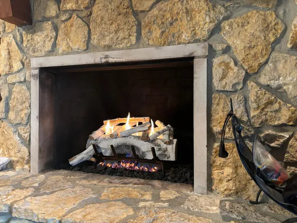 A vent-free gas log set burning in a large stone fireplace