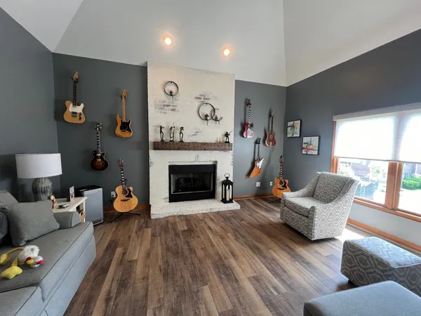 A remodeled fireplace wall in a modern living room with guitars on the wall and a wood insert below a shelf mantel