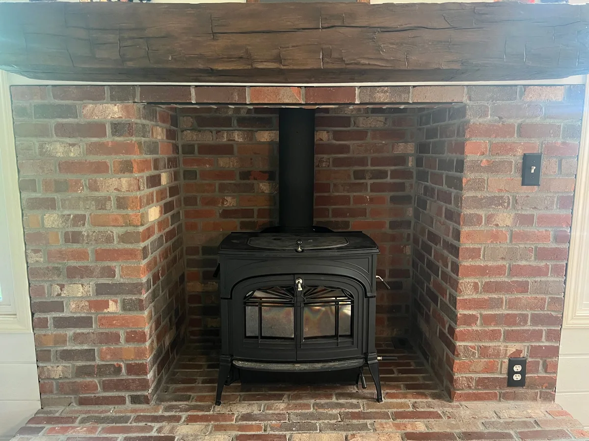 A black wood stove on a brick hearth inside a brick alcove