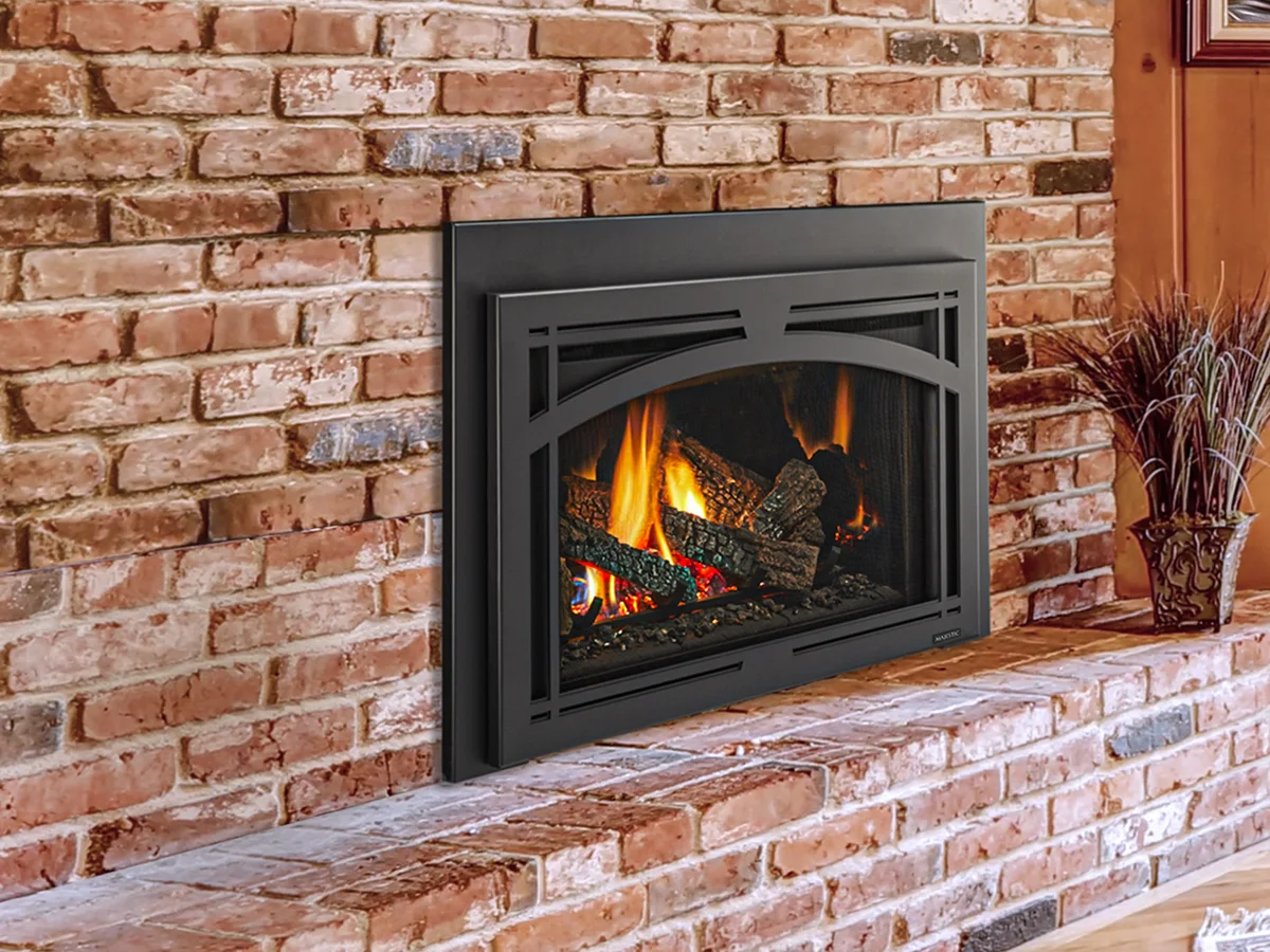 A gas insert burning in a red brick fireplace wall
