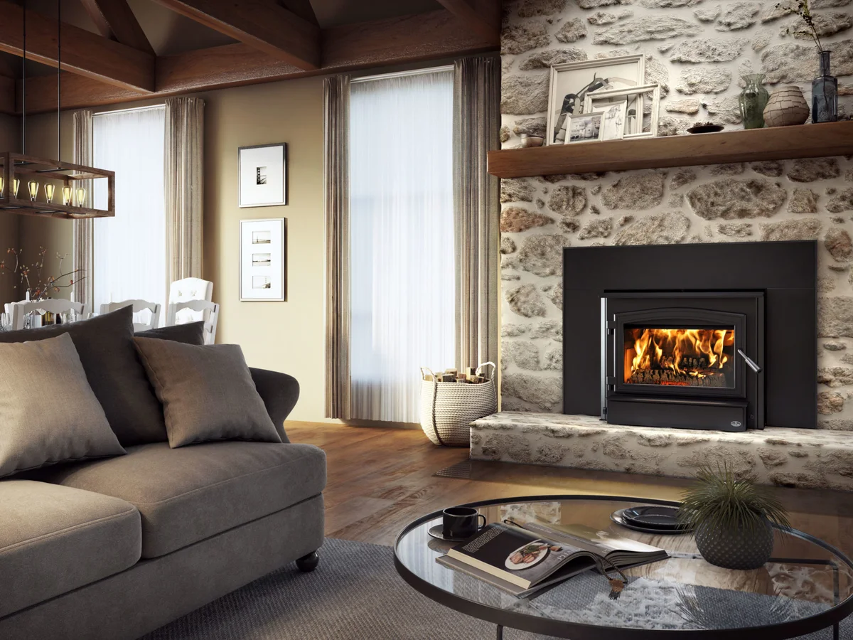 A wood insert burning in a stone fireplace wall, a sofa and coffee table in front of it