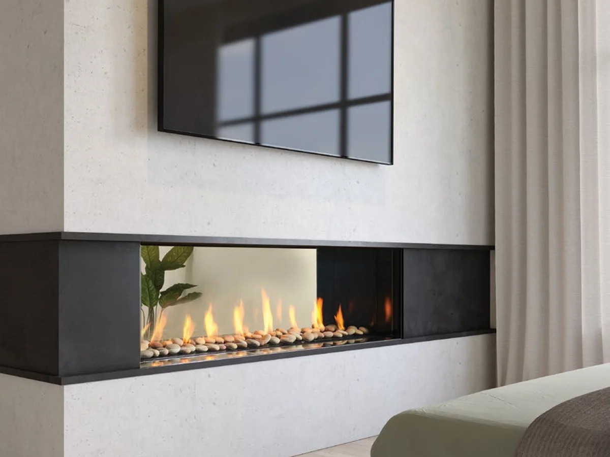 A Regency 60-inch Seattle see-through gas fireplace set into a finished wall beneath a television in a hotel-style room